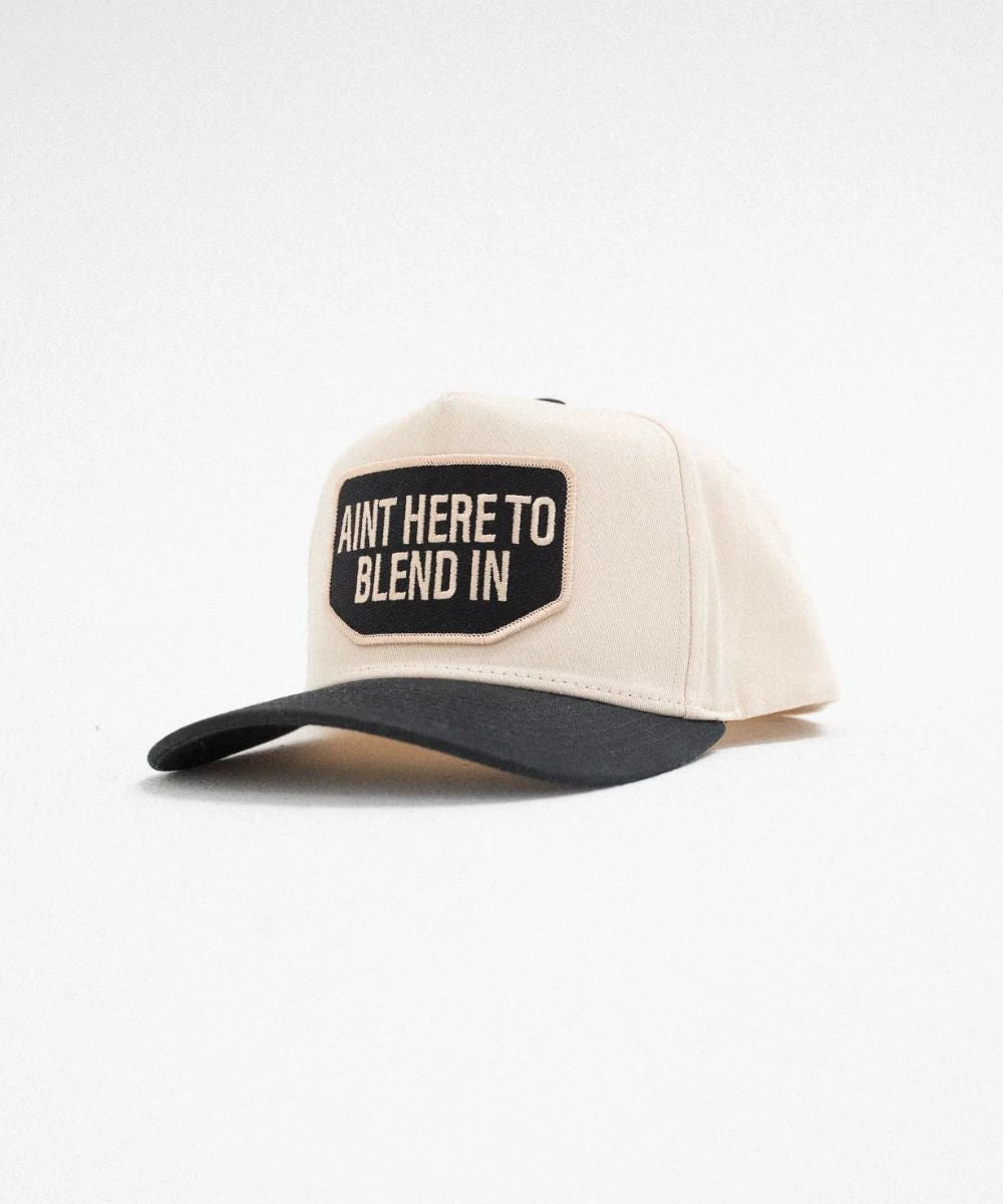 Outlier canvas trucker cap featuring a two-tone cream and black high profile shape
